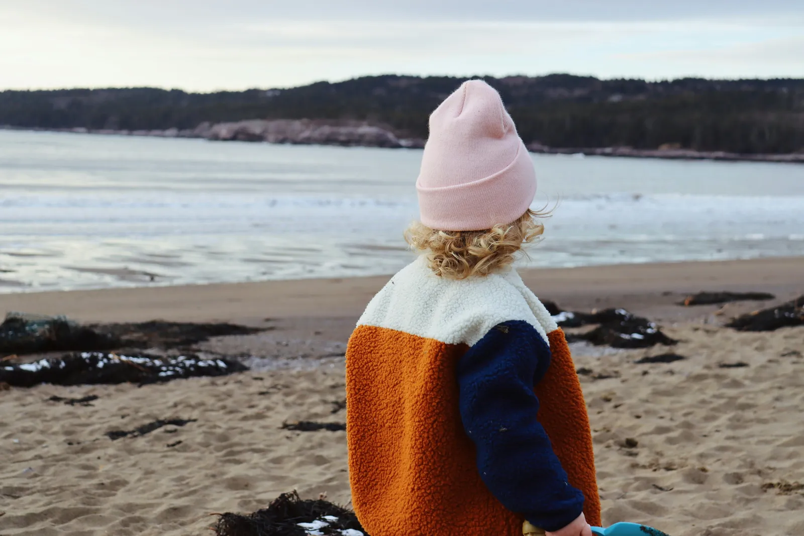 Un enfant au bonnet rose face à la mer