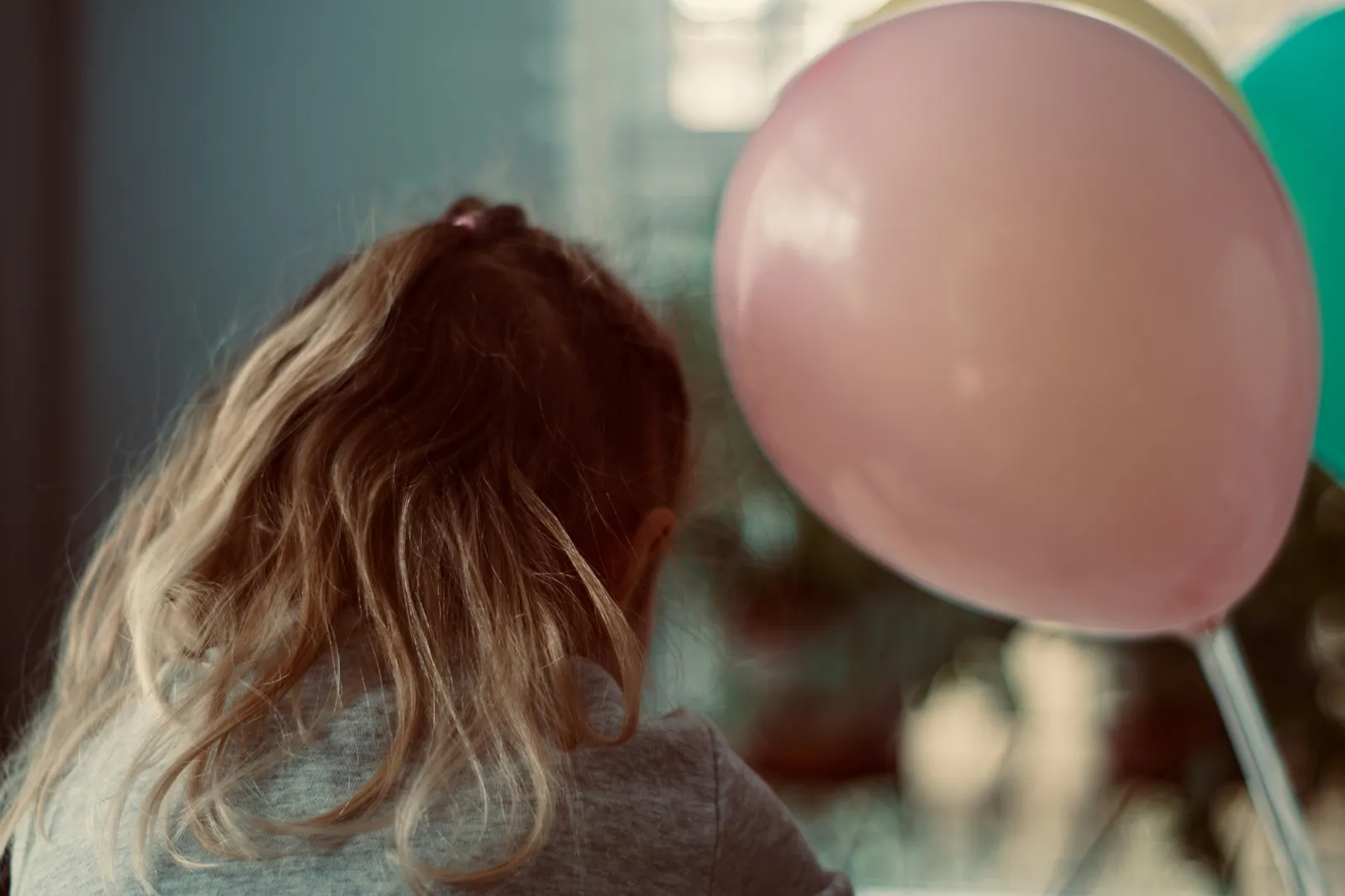 Une enfant de dos près de ballons colorés